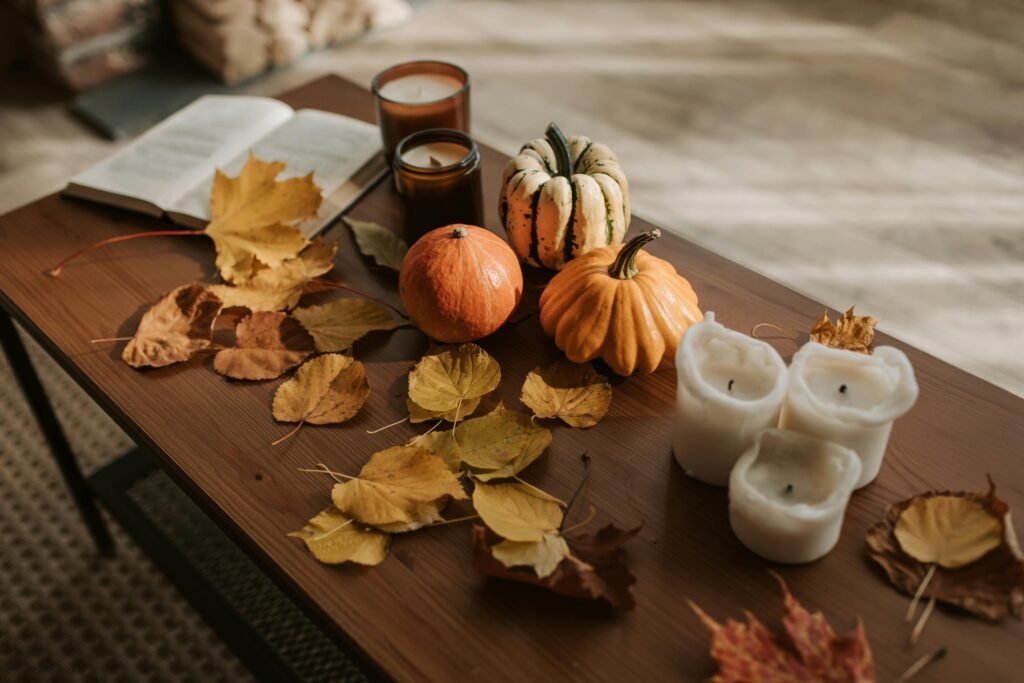 Warm autumn setting with pumpkins, candles, and leaves creating a cozy fall atmosphere.