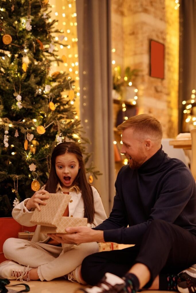 pexels-photo-5778905-5778905 A joyful father and daughter open presents together by a beautifully decorated Christmas tree indoors.
