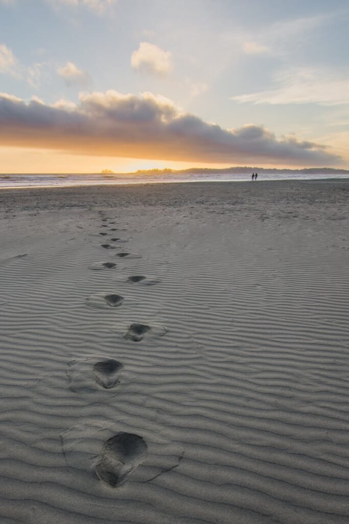 pexels-photo-1522285-1522285 Tranquil beach scene at sunset with footprints leading to the horizon.