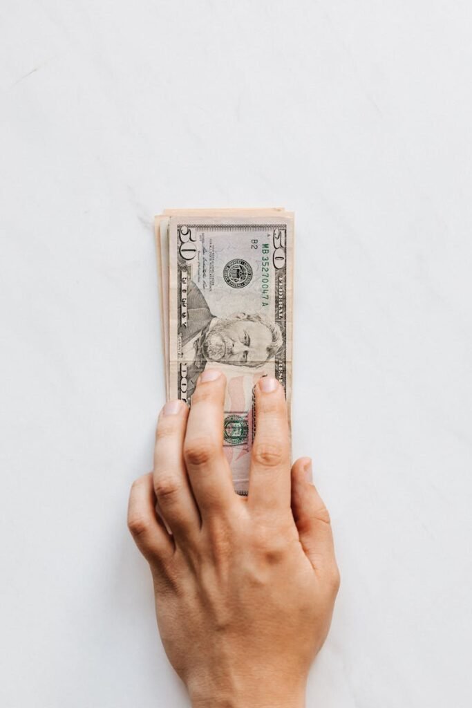 pexels-photo-4386289-4386289 A hand holds a stack of US dollar bills, symbolizing wealth and finance.