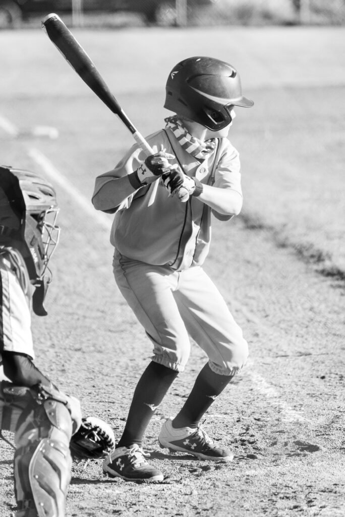 pexels-photo-7899277-7899277 Young baseball player getting ready to bat, captured in black and white on the field.