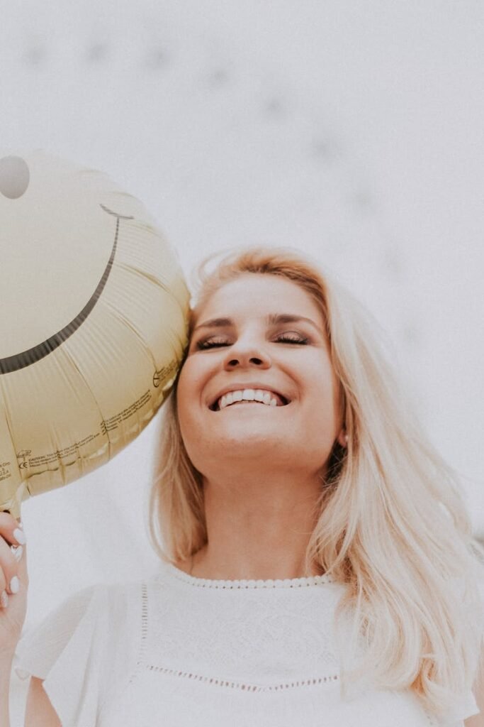 pexels-photo-1236678-1236678 Cheerful woman holding a smiley balloon outdoors on a sunny day, exuding happiness and positivity.