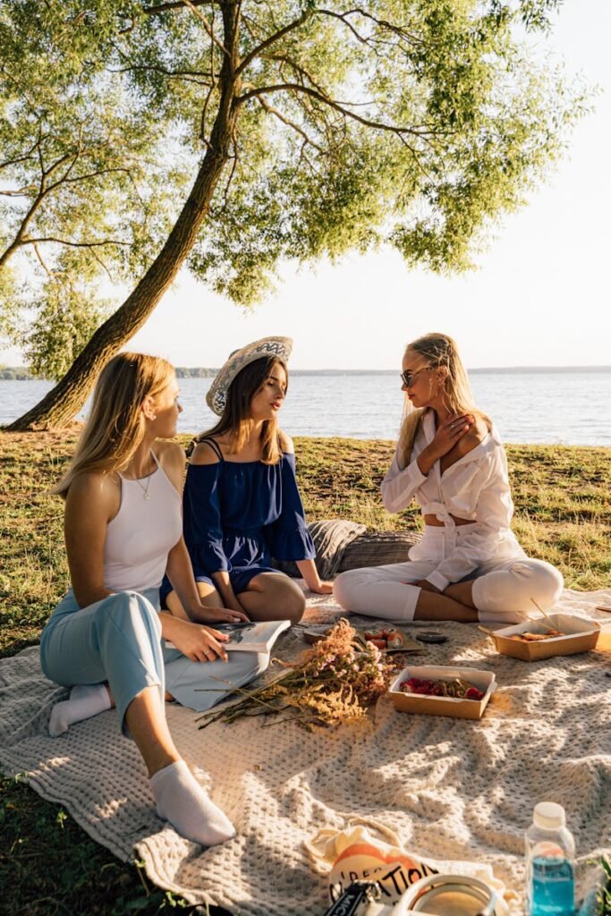 pexels-photo-4989382-4989382 Three women enjoying a serene picnic by the lake on a sunny day.