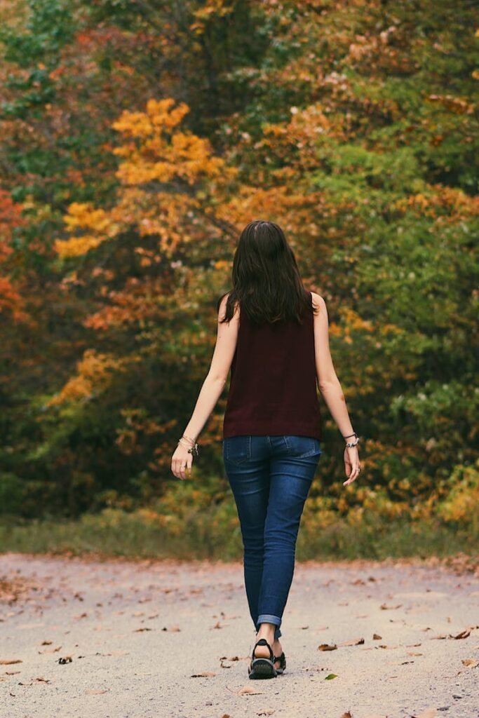 pexels-photo-906106-906106 A young woman walks down a colorful autumn forest path, surrounded by vibrant leaves.