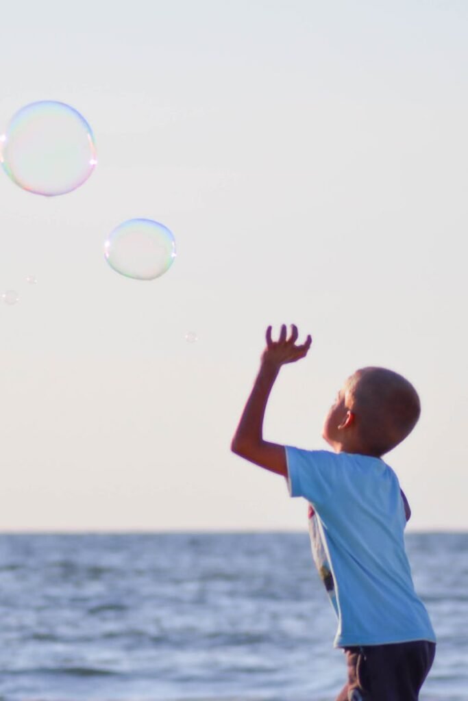 pexels-photo-106684-106684 A joyful child playing with bubbles by the ocean on a sunny day, embodying the spirit of summer fun.