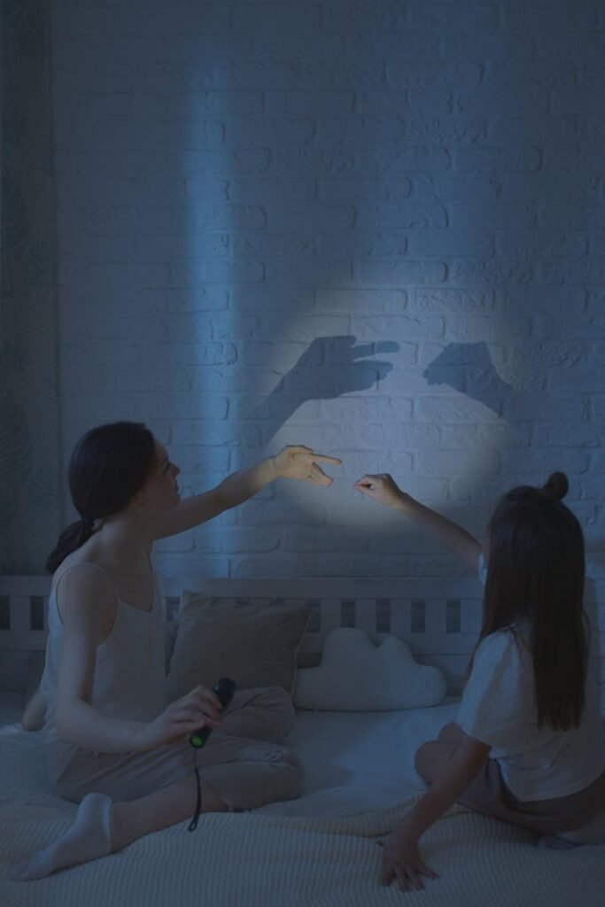 pexels-photo-7505161-7505161 A mother and daughter create shadow puppets on a bedroom wall, enjoying a nighttime play session.