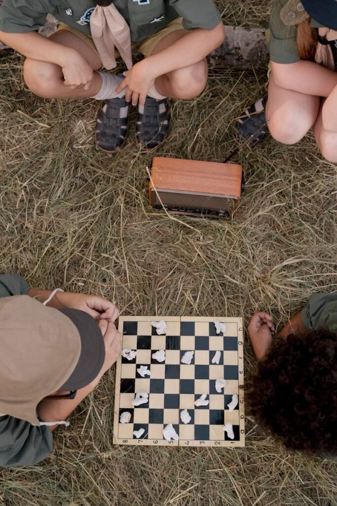 pexels-photo-9303629-9303629 Overhead view of children playing chess surrounded by nature, capturing a fun camping moment.