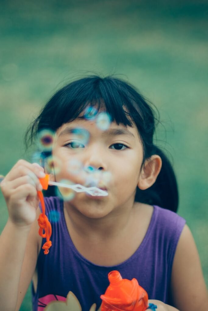 pexels-photo-333529-333529 Adorable young girl enjoying summer outdoors while blowing bubbles, capturing pure childhood joy.